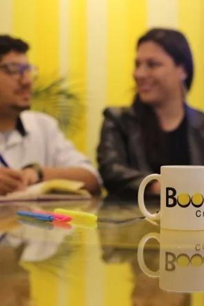 Reunião de planejamento da equipe BOOOM Criative, com caderno, canetas e caneca da agência.