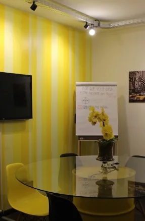 Sala amarela da BOOOM Criative preparada para reuniões e planejamento estratégico.