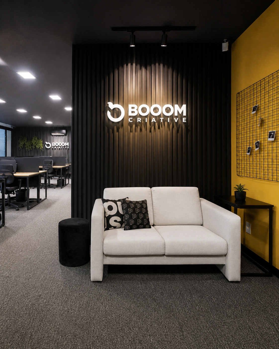 Recepção da BOOOM Criative em Curitiba, com marca iluminada e área de espera.