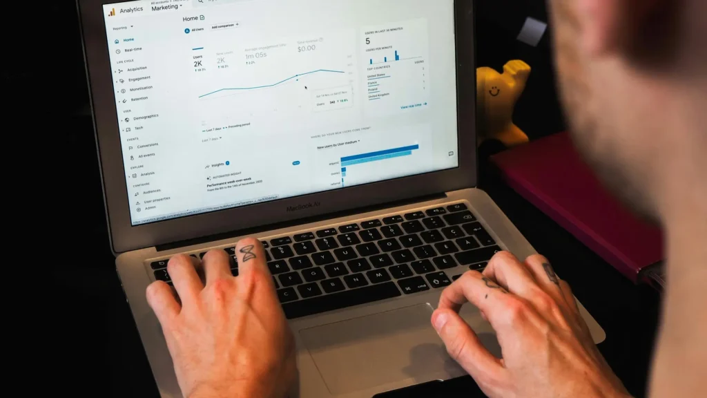 Profissional consulta gráficos de desempenho de marketing no Google Analytics em um notebook.